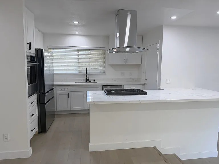 Remodeled white kitchen with island, gas range and premium appliances